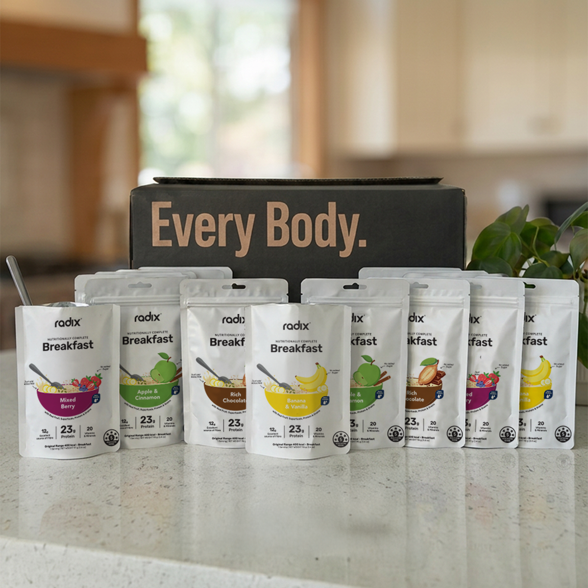 Row of radix 28 Strong Start breakfast meal replacement packs on a kitchen counter with 'Every Body' branding in the background.